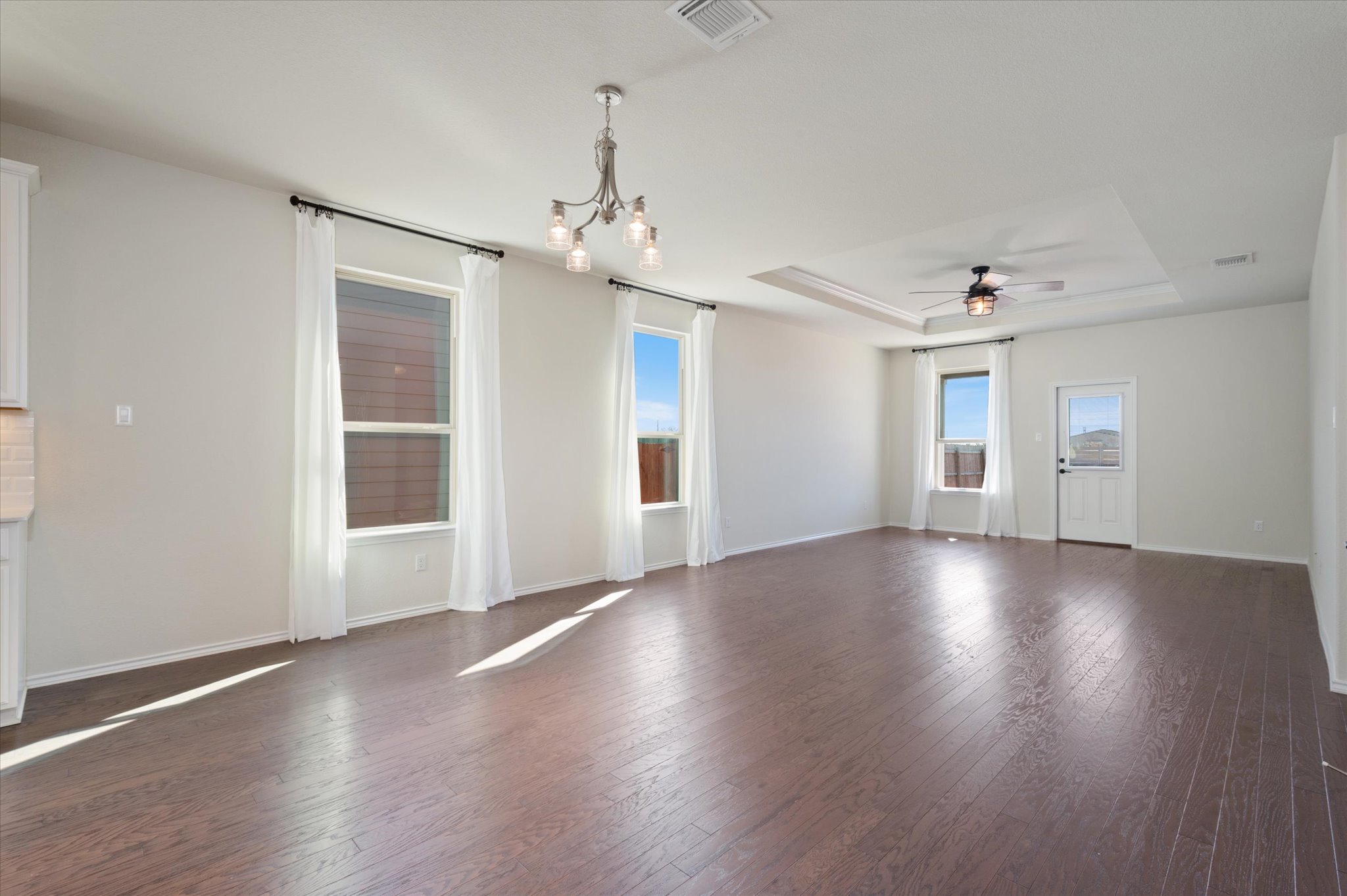 2044 Cliffbrake Way Georgetown, TX 78626 - Photo 12 of 40 Empty room with a raised ceiling, dark wood finished floors, a ceiling fan, and suspended lighting