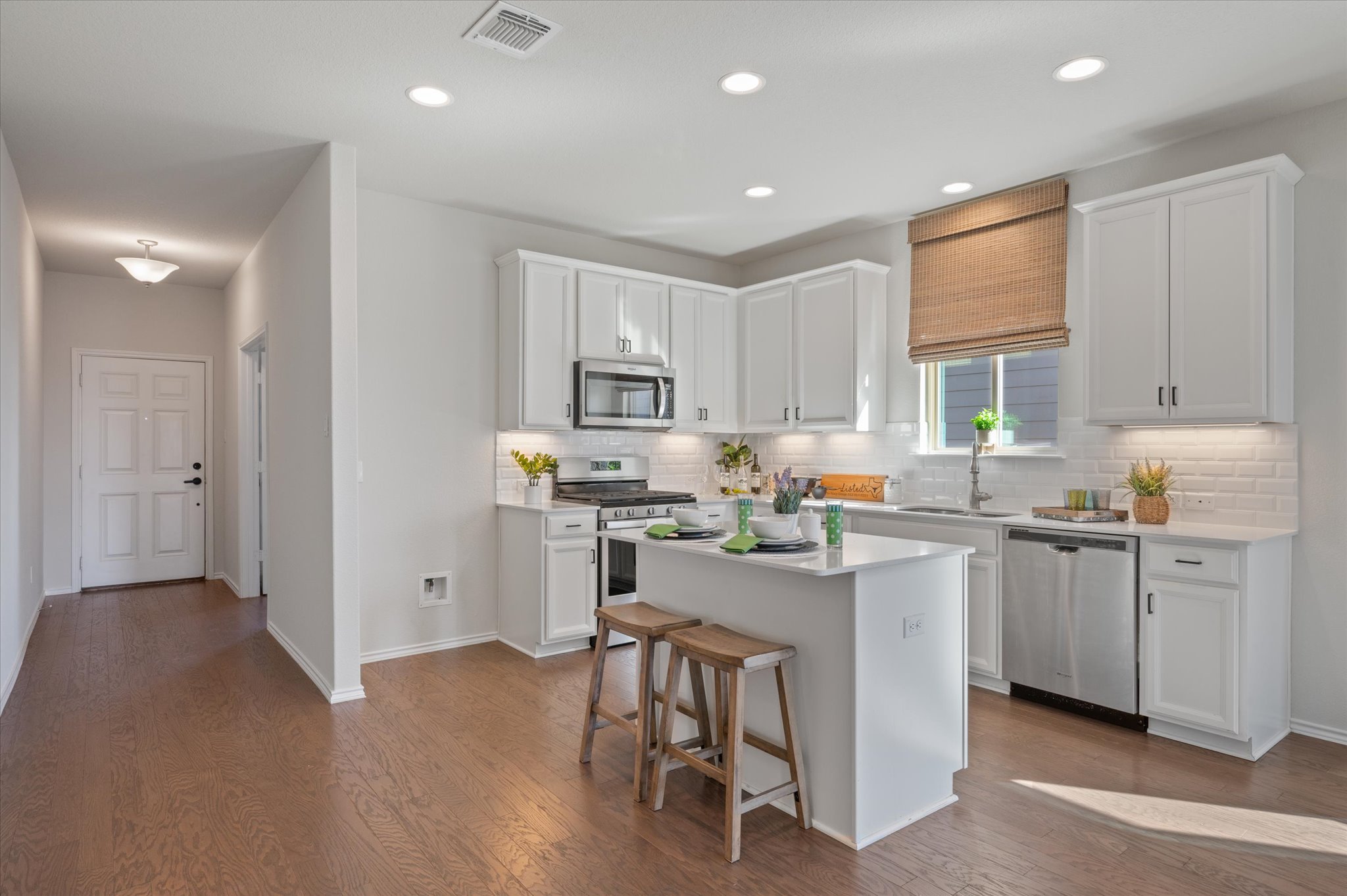 2044 Cliffbrake Way Georgetown, TX 78626 - Photo 7 of 40 Kitchen with white cabinetry, stainless steel appliances, a breakfast bar, a center island, and dark wood flooring
