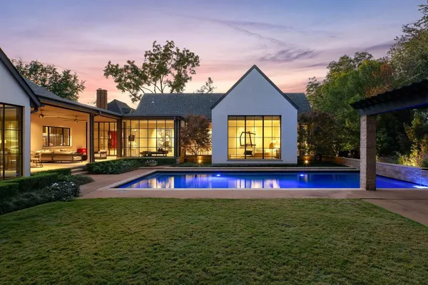 a view of swimming pool with red chairs in front of house
