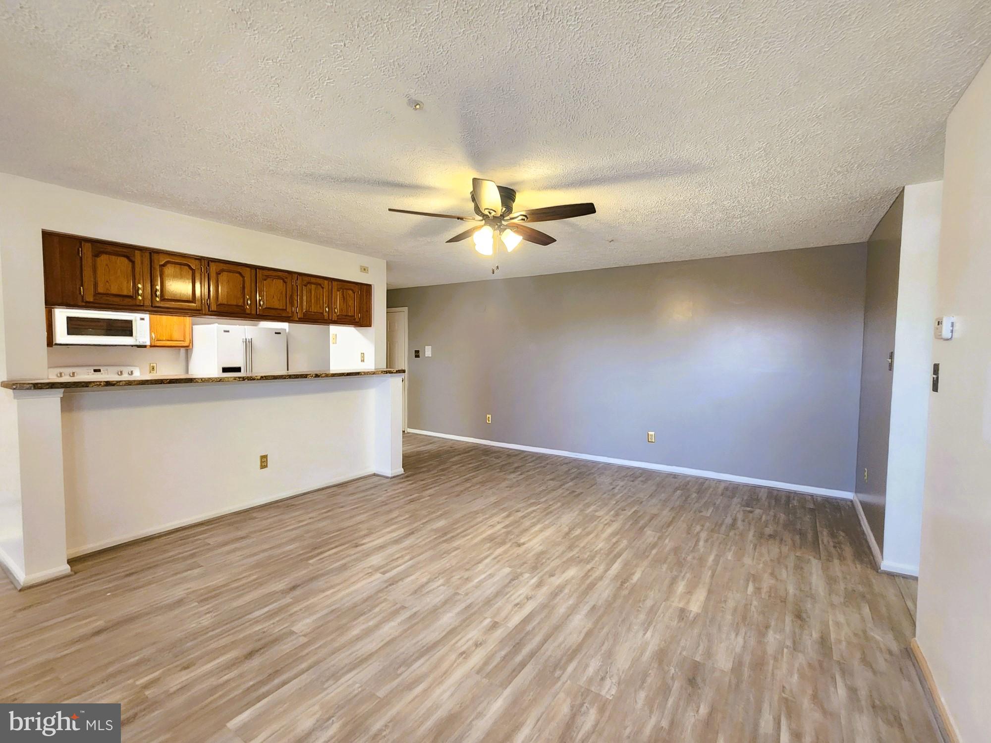 13 Locust Path Court, Unit 813 Nottingham, MD 21236 - Photo 3 of 23 a view of a kitchen with wooden floor and a ceiling fan