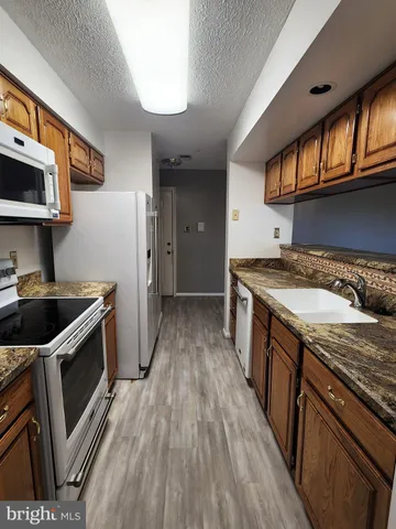 a kitchen with granite countertop a sink a stove top oven and wooden floor