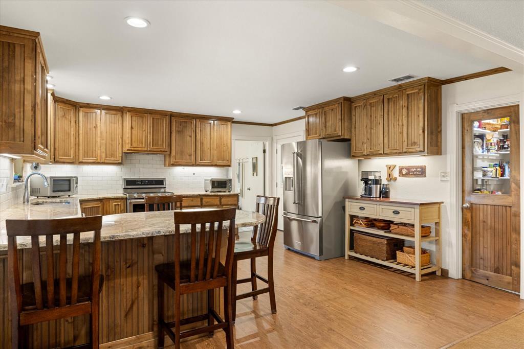 17305 Highway 281 Hico, TX 76457 - Photo 7 of 28 a kitchen with stainless steel appliances a stove a sink refrigerator and a refrigerator with wooden floor