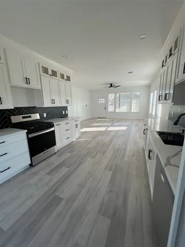 a large kitchen with cabinets wooden floor and stainless steel appliances