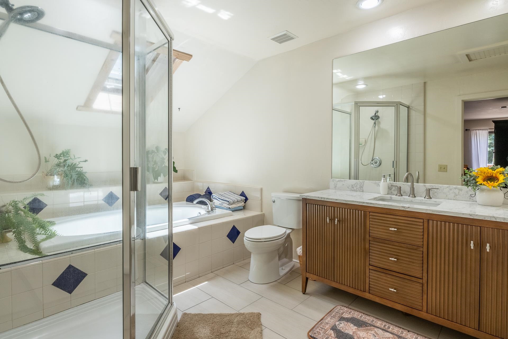 537 Aspen Spring Ranch Road Mammoth Lakes, CA 93546 - Photo 17 of 40 Bathroom featuring a glass-enclosed shower, a built-in bathtub with tiled surround, a skylight, a single vanity with a stone countertop, and tile flooring
