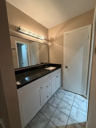 a bathroom with a granite countertop sink a mirror and a shower