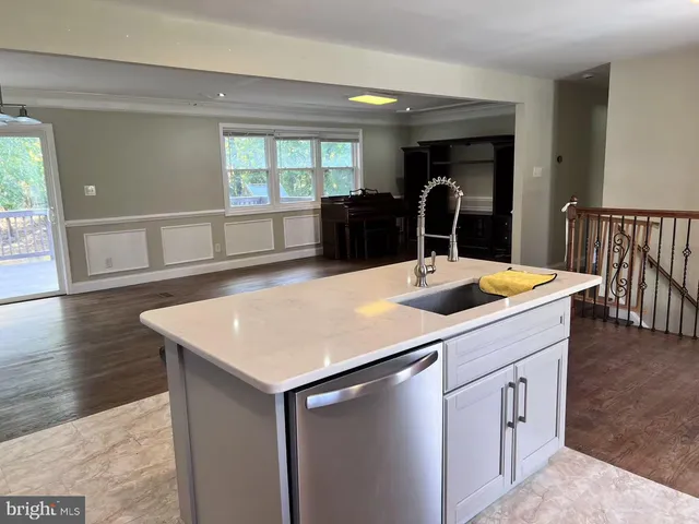 a kitchen with a sink a large counter and wooden floor