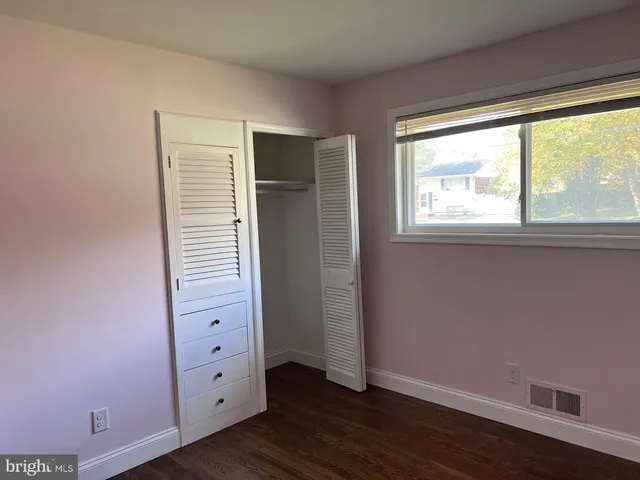 an empty room with wooden floor closet and windows