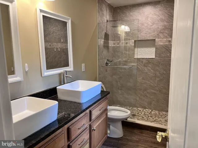 a bathroom with a granite countertop sink toilet a mirror and shower