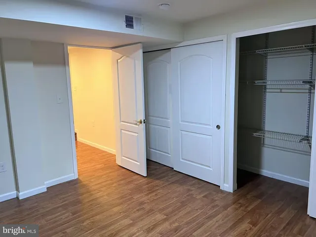 an empty room with wooden floor closet and a bathroom