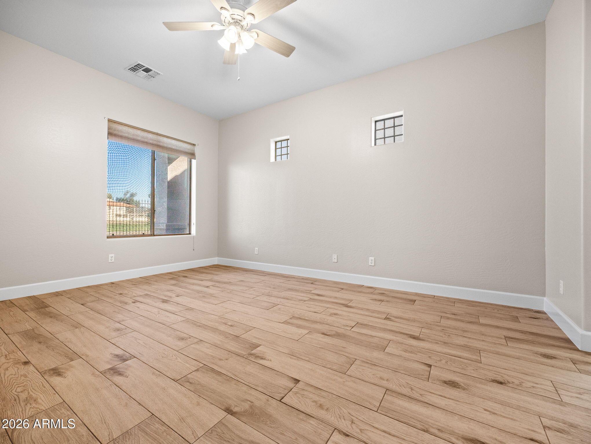 6202 East McKellips Road, Unit 83 Mesa, AZ 85215 - Photo 14 of 54 a view of an empty room with wooden floor and a window