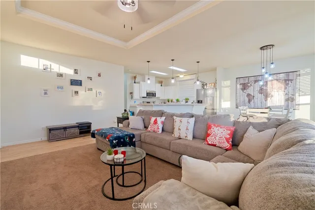 a living room with furniture kitchen view and a chandelier
