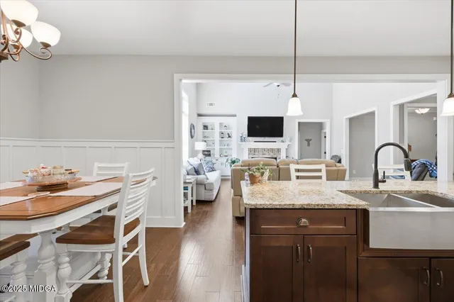 a dining room with wooden floor a chandelier a wooden table and chairs