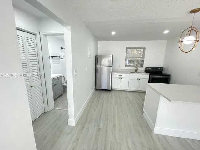 a kitchen with a refrigerator a stove and wooden floor