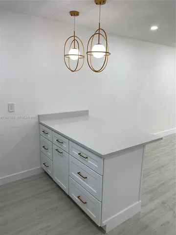 a view of a chandelier fan and utility room with wooden floor