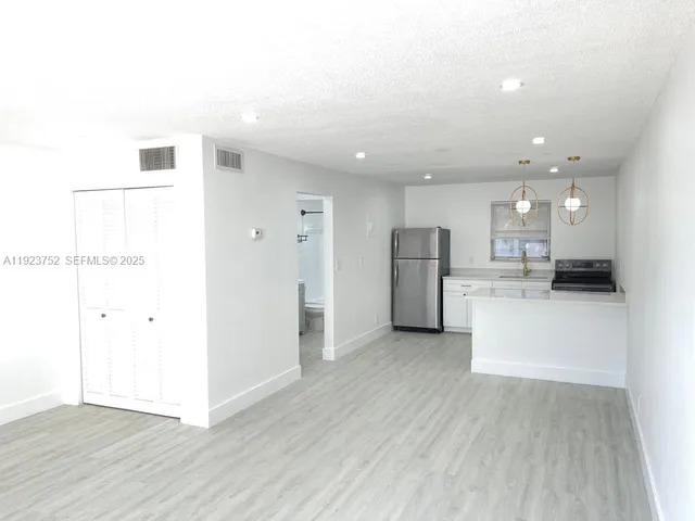 a view of a kitchen with refrigerator and white cabinets