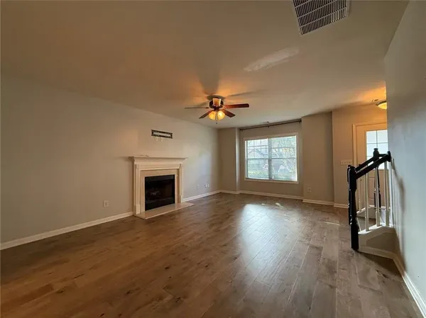 a view of an empty room with wooden floor fireplace and a window