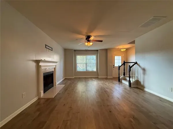 an empty room with windows a fireplace and wooden floor