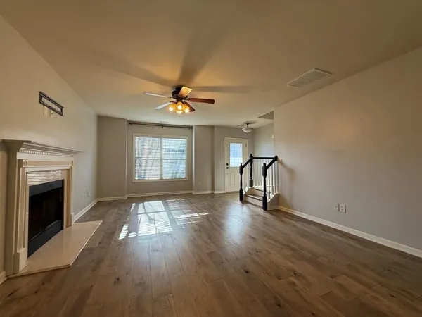 a view of an empty room with wooden floor fireplace and a window