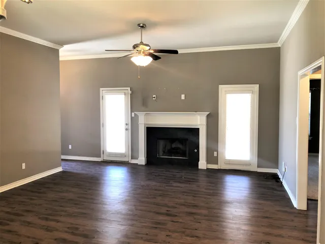 an empty room with wooden floor fireplace and window