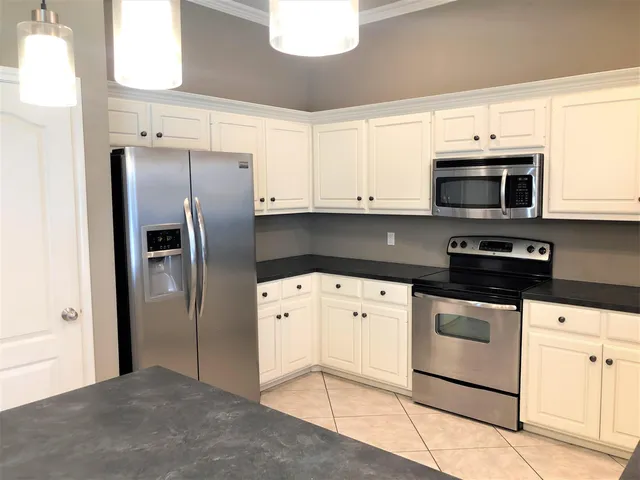 a kitchen with granite countertop white cabinets and stainless steel appliances