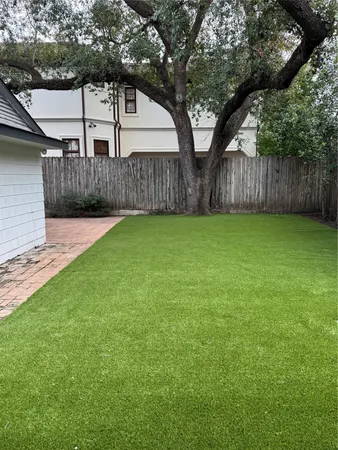 a view of a backyard with large trees and wooden fence