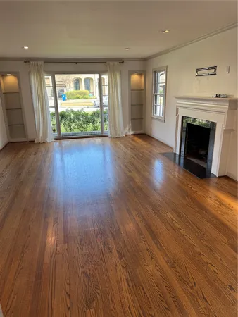an empty room with wooden floor fireplace and windows
