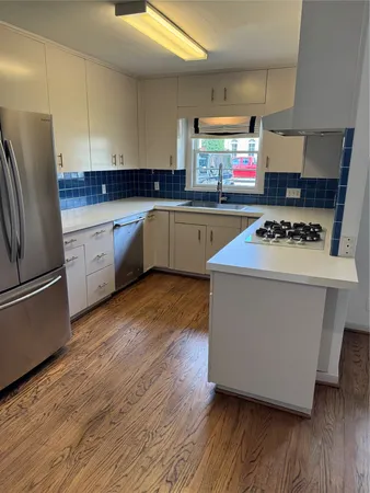 a kitchen with wooden floors and white stainless steel appliances