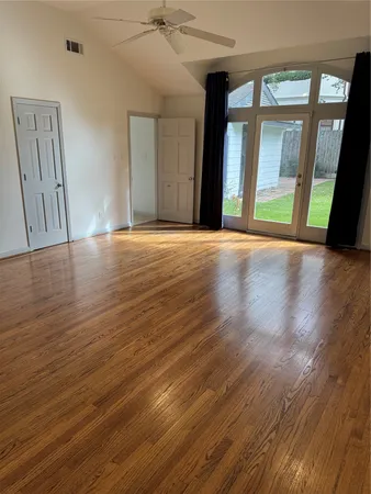 a view of an empty room with wooden floor and a window