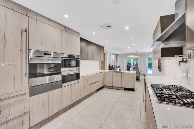 a patio with table and chairs and potted plants
