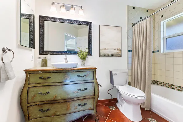 a bathroom with a toilet a sink a mirror a shower and vanity