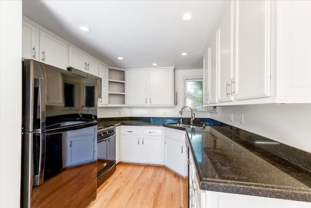 a kitchen with granite countertop a sink stainless steel appliances and white cabinets