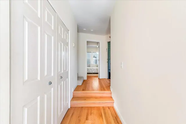a view of a hallway with wooden floor and a chandelier