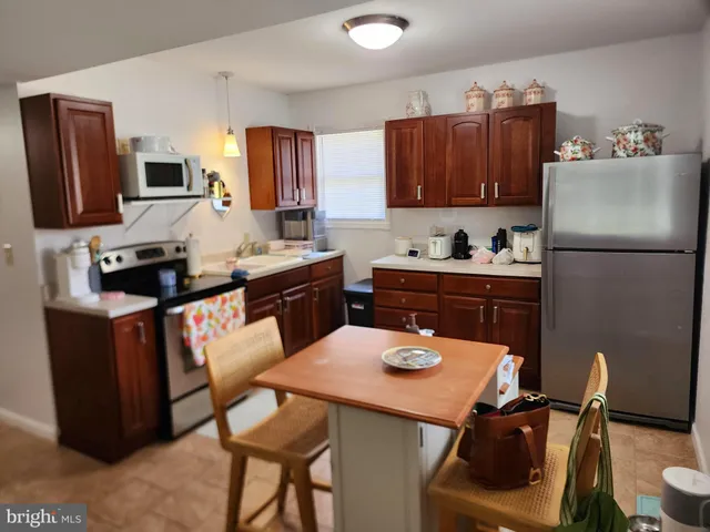 a kitchen with a refrigerator a stove a sink dishwasher with a dining table and chairs with wooden floor