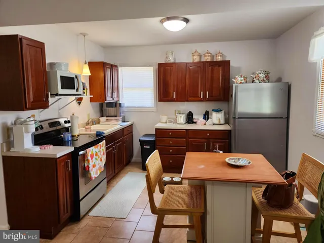 a kitchen with stainless steel appliances a stove refrigerator sink cabinets and dining table