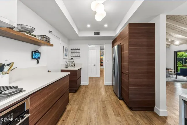 a large kitchen with stainless steel appliances a large counter top a stove and a refrigerator