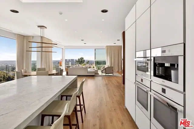 a kitchen with stainless steel appliances a dining table chairs a sink and white cabinets next to a window