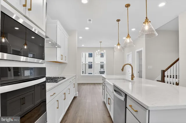 a kitchen with stainless steel appliances a sink a stove top oven a counter space and cabinets