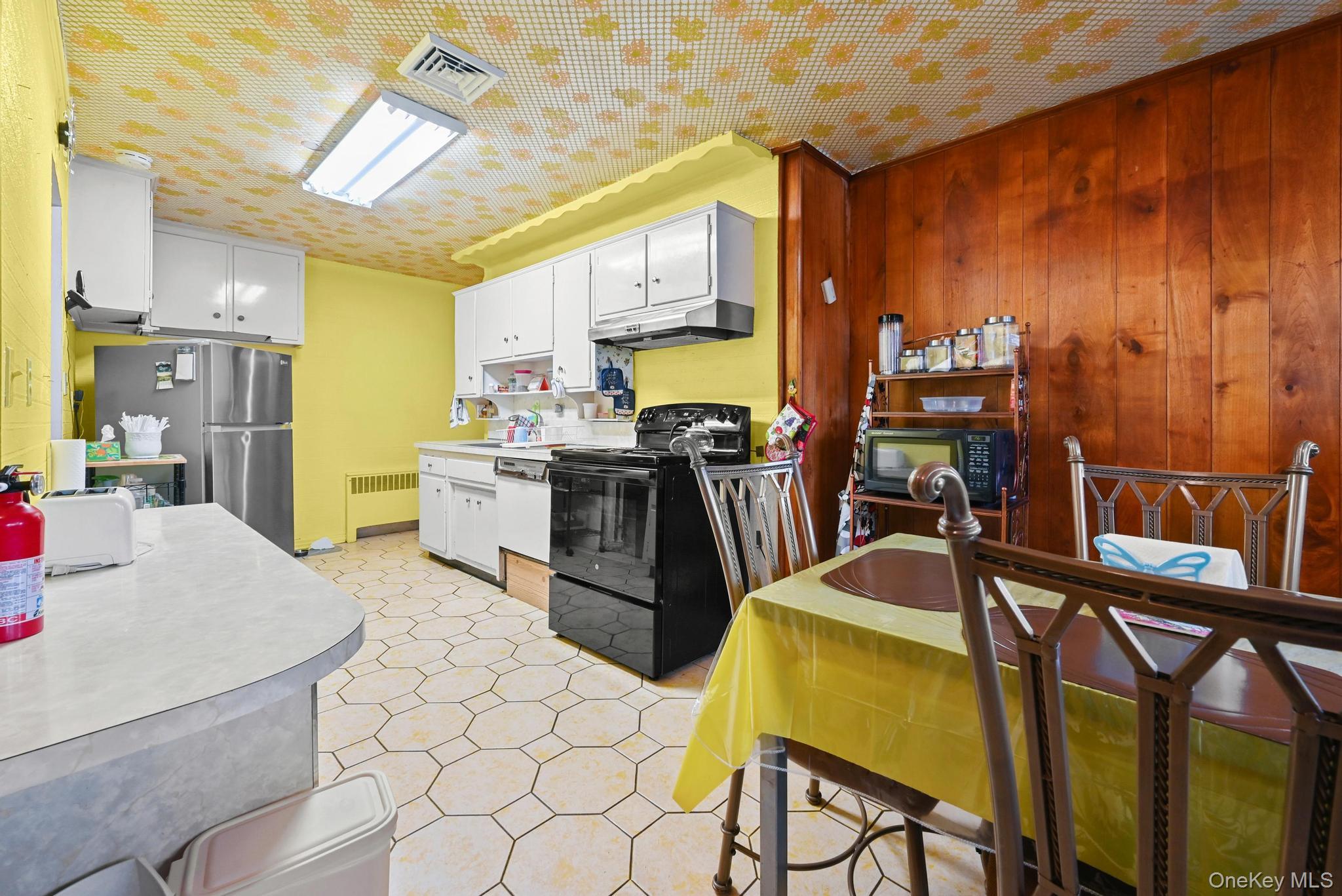 2225 Leighton Road Elmont, NY 11003 - Photo 14 of 26 a kitchen with stainless steel appliances kitchen island granite countertop a table chairs and a refrigerator