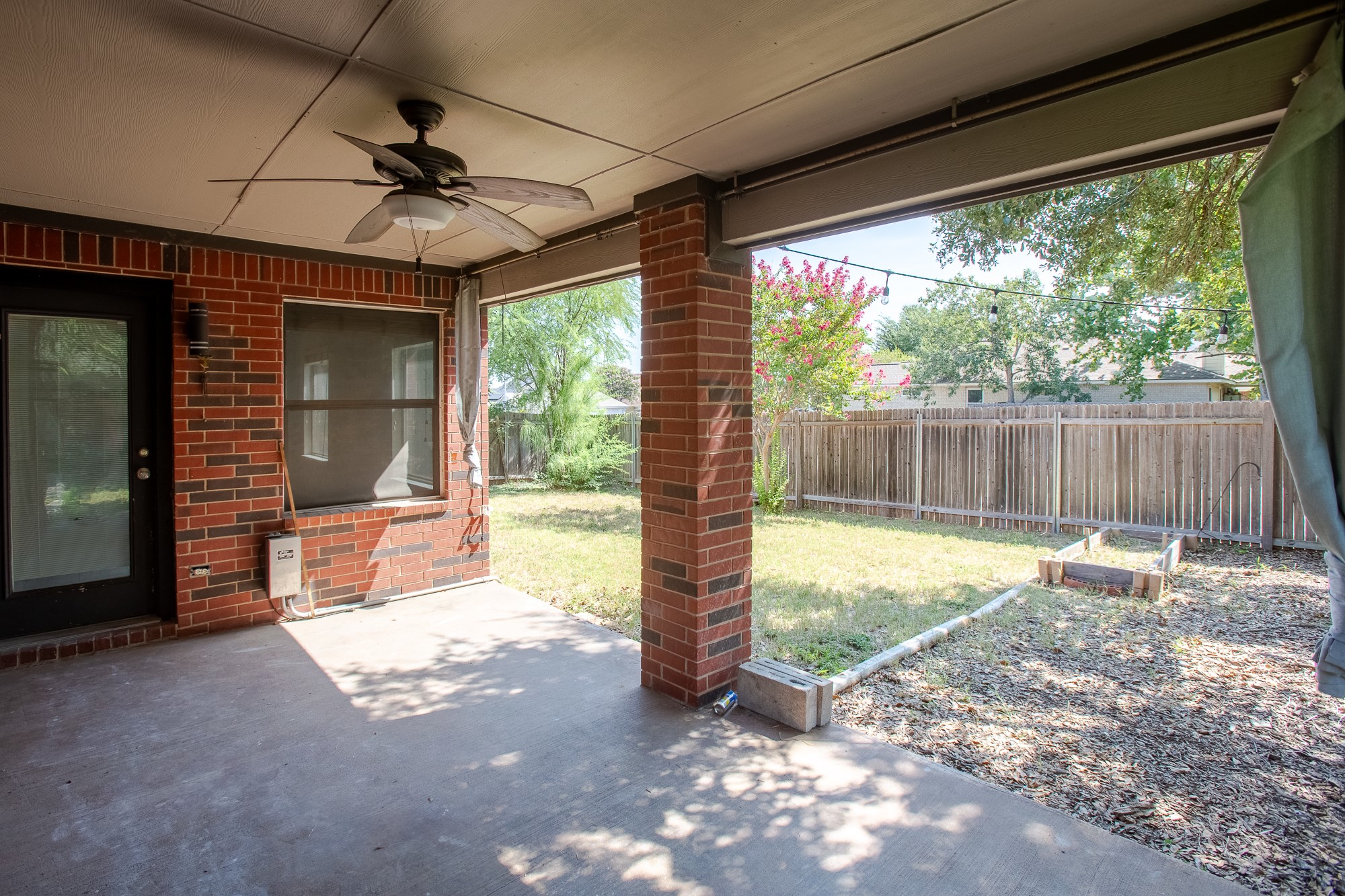 1201 Springbrook Road Pflugerville, TX 78660 - Photo 29 of 33 A comfortable covered patio extends to a private fenced yard, ideal for outdoor relaxation.