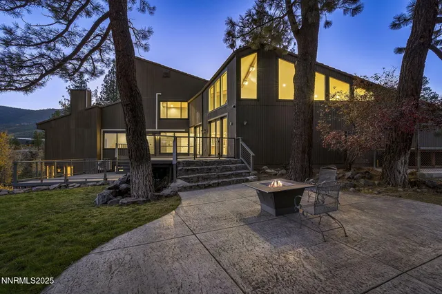 a view of a brick house with a small yard and a large tree