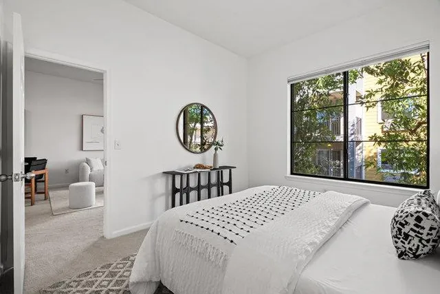 a bedroom with a bed painting and a large window