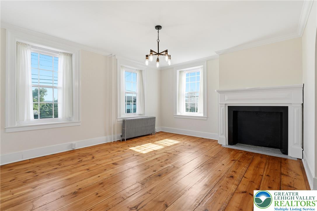 4682 Steuben Road Bethlehem, PA 18020 - Photo 8 of 79 Natural light streams into this generously proportioned room, highlighting the warm wood flooring and elegant fireplace.