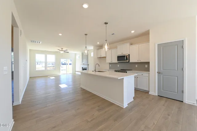 a large kitchen with stainless steel appliances granite countertop a large counter top a sink and a refrigerator