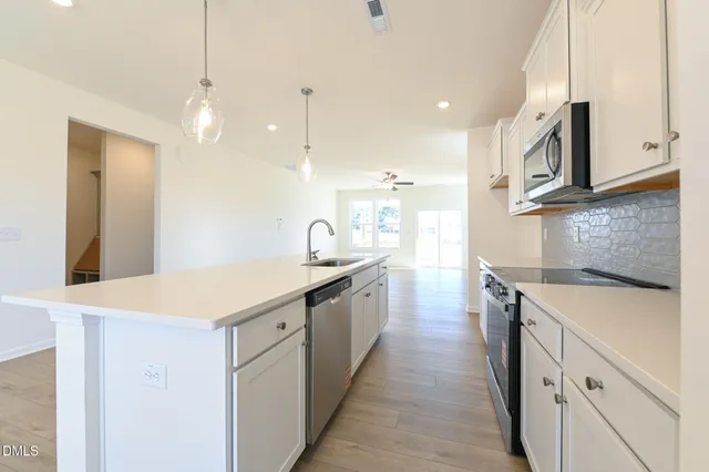 a kitchen with stainless steel appliances granite countertop a stove a white cabinet and a granite counter tops