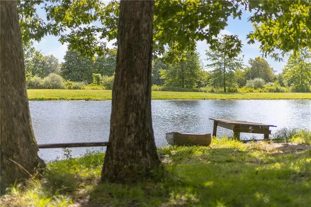 a view of a lake in front of house with yard and outdoor seating