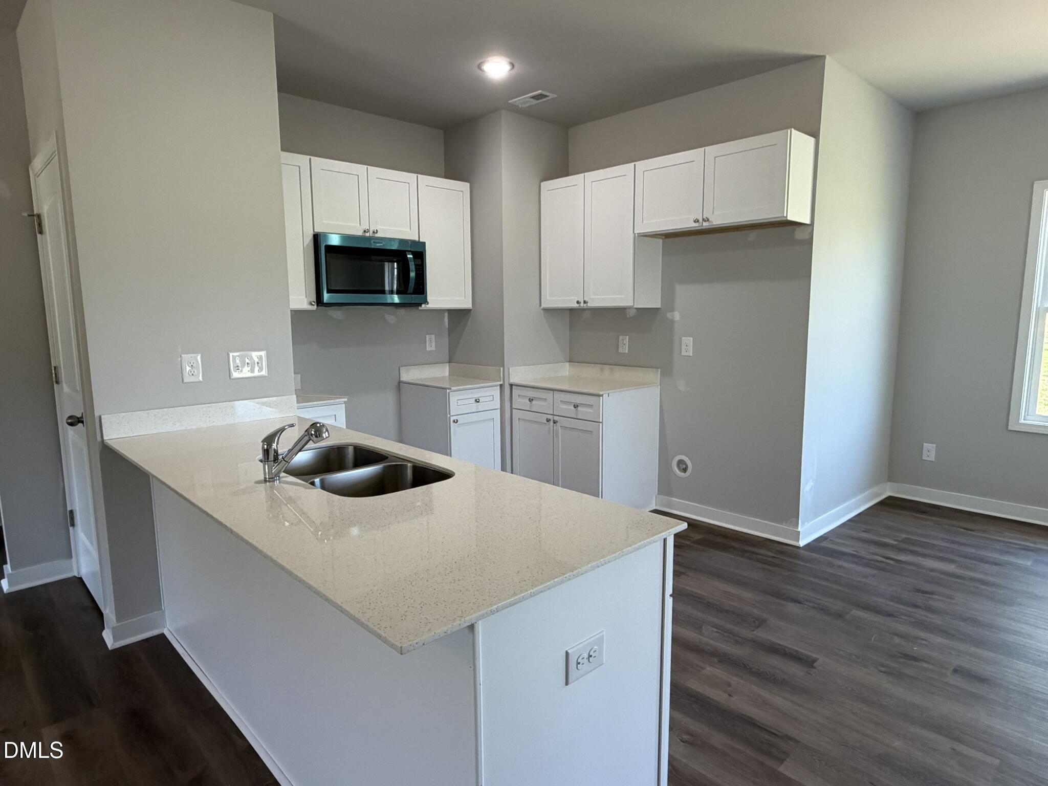 25 Jacobs Ridge Drive Four Oaks, NC 27524 - Photo 3 of 18 a kitchen with a sink a stove a microwave and cabinets