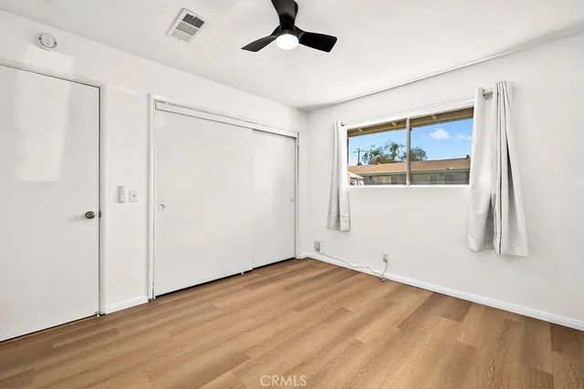 a view of empty room with wooden floor and fan