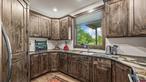 a kitchen with stainless steel appliances granite countertop a sink window and cabinets