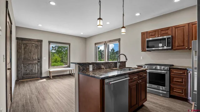 a kitchen with stainless steel appliances granite countertop a stove a sink and a microwave