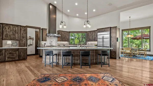 a kitchen with stainless steel appliances granite countertop a stove top oven a sink a dining table and chairs with wooden floor